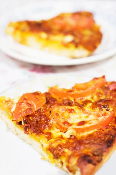 En bit pizza med tomat och ost på tallrik — Stockfoto