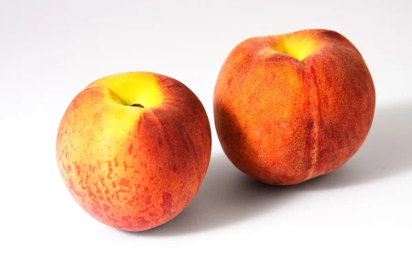 Twee lekkere sappige perziken op een witte achtergrond — Stockfoto