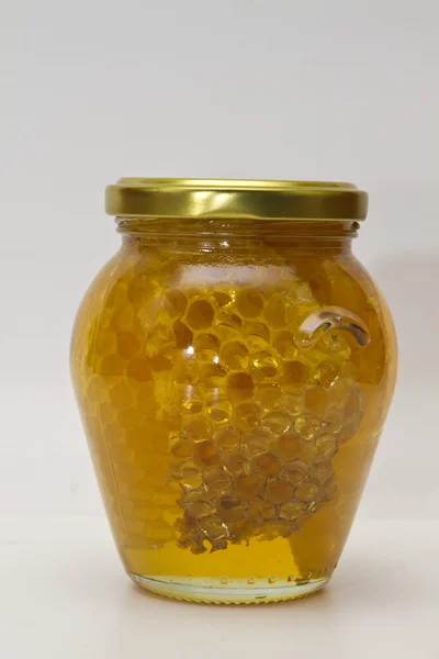 Medová sklenice na bílém pozadí — Stock fotografie