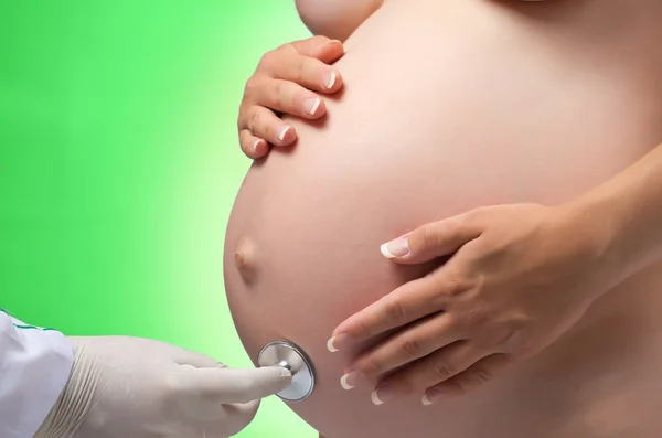 Zwangere vrouw wordt onderzoeken door een arts met een stethoscoop. — Stockfoto