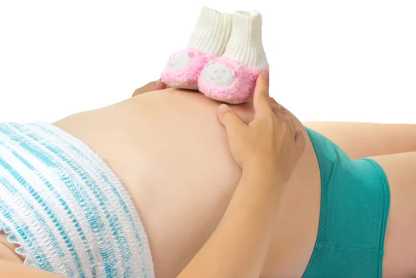 Pregnant woman holding pink booties on her belly. — Stock Photo, Image