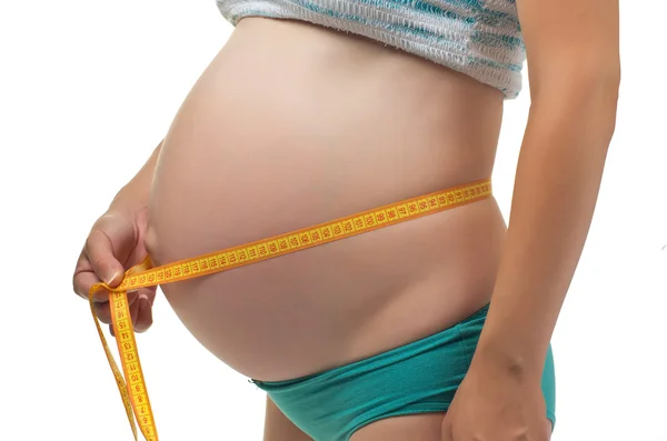 Gravid kvinna mäter sin mage. — Stockfoto