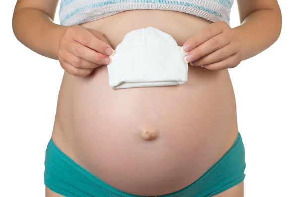 Close-up of pregnant woman holding white baby hat in hand — Stock Photo, Image
