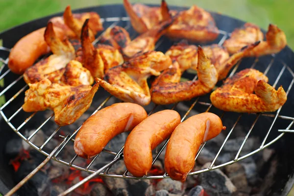 Sausages and chicken wings on the grill — Stock Photo, Image