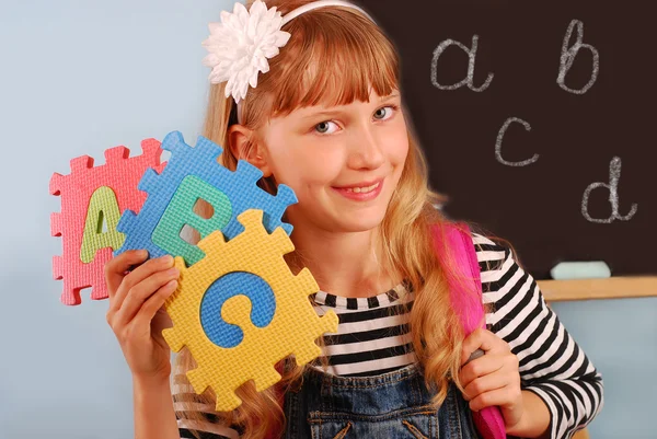 Colegiala sosteniendo letras puzzle — Foto de Stock