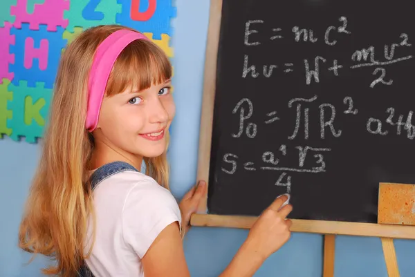Genie schoolmeisje schrijven op blackboard — Stockfoto