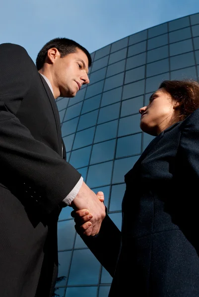 Handshake obchodní muž a žena na moderní budova pozadí — Stock fotografie