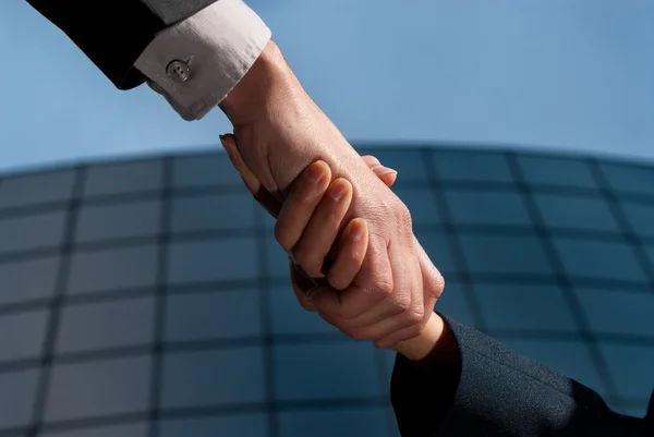Handshake homem de negócios irreconhecível e mulher no backgrou edifício moderno — Fotografia de Stock