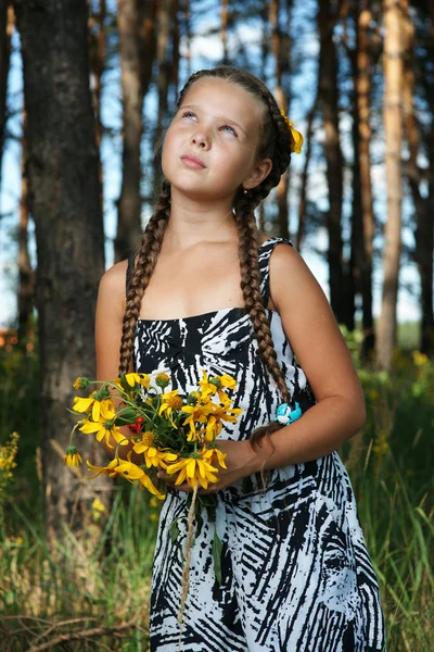 Het meisje in hout met een bos van bloemen — Stockfoto