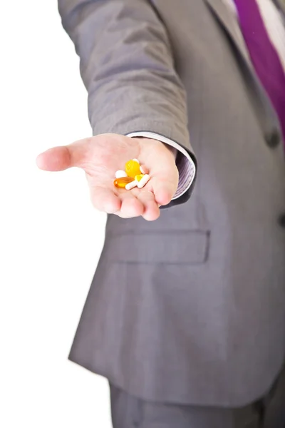 Homem de terno segurando pílulas isoladas em branco — Fotografia de Stock
