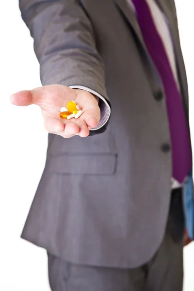 Homem de terno segurando pílulas isoladas em branco — Fotografia de Stock