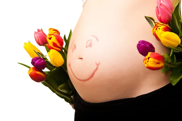 Schwangerer Bauch mit Tulpenblüten — Stockfoto