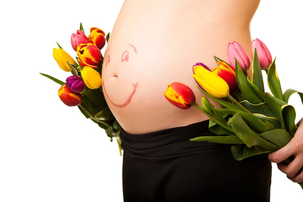 Schwangerer Bauch mit Tulpenblüten — Stockfoto