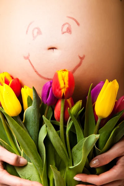 Donna incinta pancia con fiori di tulipano — Foto Stock