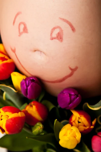 Gravid kvinna mage med tulpan blommor — Stockfoto