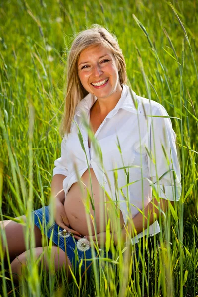 Yeşil alan üzerinde oturan hamile kadın — Stok fotoğraf