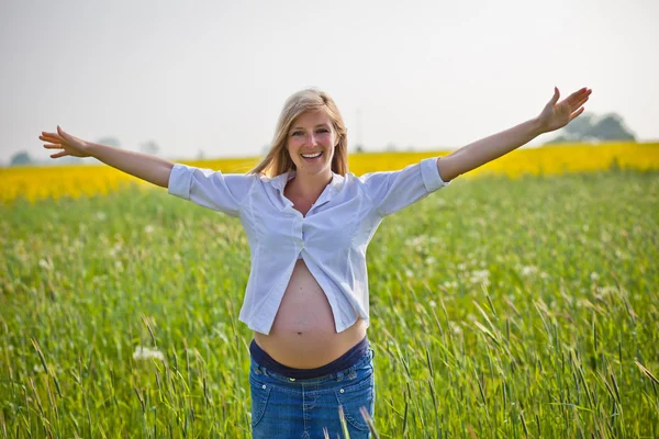 Donna incinta seduta sul campo verde — Foto Stock