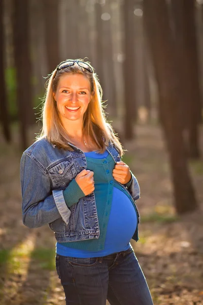Mujer embarazada sentada en el campo verde —  Fotos de Stock