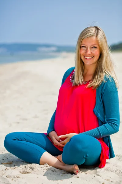 Gravid kvinna sitter på gröna fält — Stockfoto