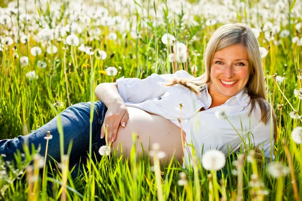 Pregnant woman sitting on green field — Stock Photo, Image