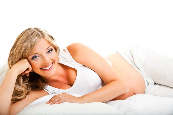 Mujer embarazada en cama aislada en blanco — Foto de Stock
