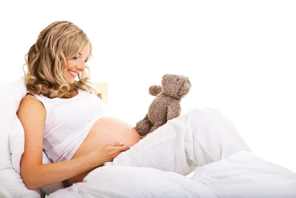 Беременная женщина в постели изолированы на белом — стоковое фото