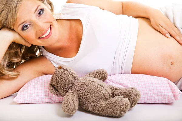 Έγκυος γυναίκα στο κρεβάτι που απομονώνονται σε λευκό — Φωτογραφία Αρχείου