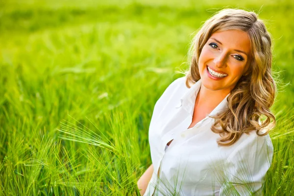 Blond kvinna porträtt utomhus på gröna fält — Stockfoto