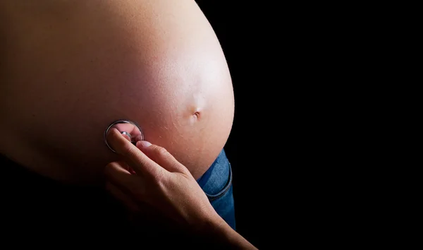 Zwangere vrouw op zwarte achtergrond Rechtenvrije Stockfoto's