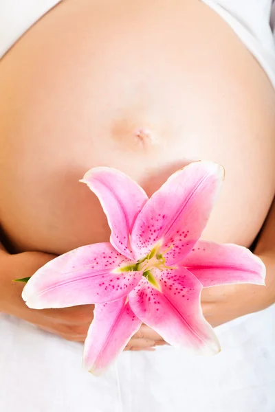 Mujer embarazada sosteniendo lirios aislados en blanco —  Fotos de Stock