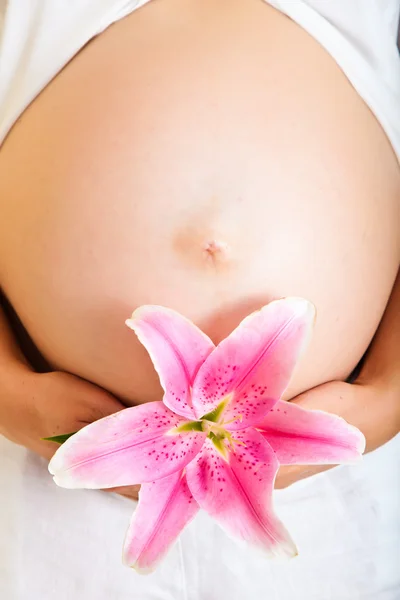 Schwangere hält Lilien isoliert auf weißem Grund — Stockfoto