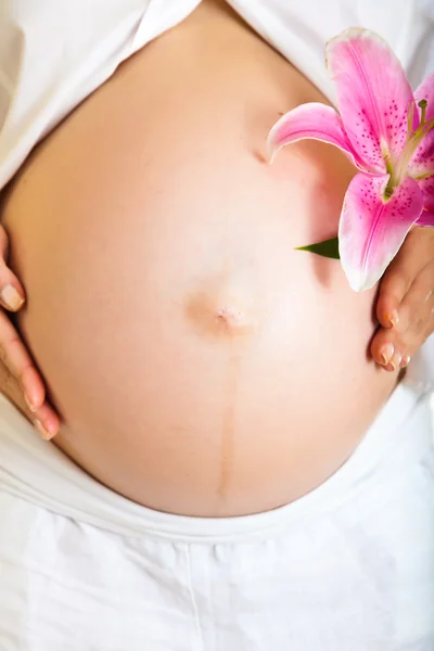 Donna incinta che tiene i lillies isolati su bianco — Foto Stock