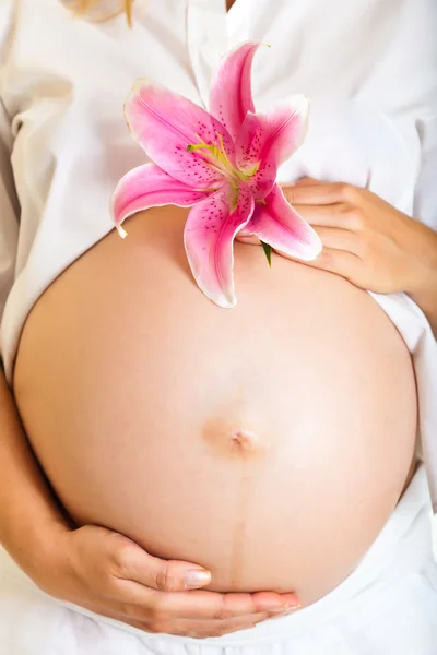 Έγκυος γυναίκα που κρατά lillies απομονωθεί σε λευκό — Φωτογραφία Αρχείου