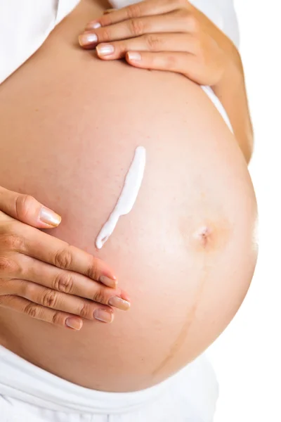 Kobieta w ciąży brzuch nawilżające, aby uniknąć rozstępów na białym tle — Zdjęcie stockowe