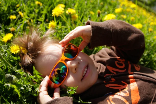 Niño en gafas de sol acostado en el prado Fotos de stock