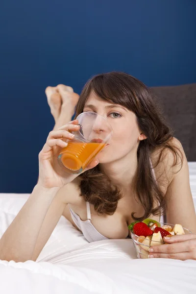 Beber jugo de naranja en la cama — Foto de Stock