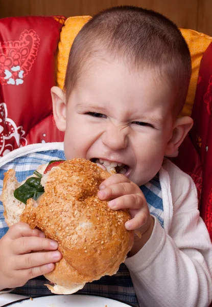 Lilla pojken äta hamburgare — Stockfoto