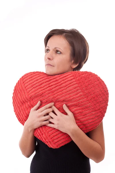 Vrouw omarmen een hart-vorm-kussen — Stockfoto