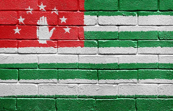 レンガの壁にアブハジア自治共和国の旗 — ストック写真