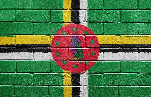 レンガの壁にドミニカ国の国旗 — ストック写真