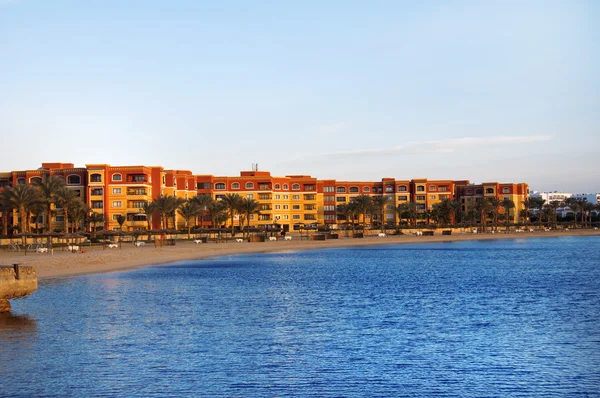 Praia de areia com palmeiras e grandes casas de férias ao pôr do sol — Fotografia de Stock