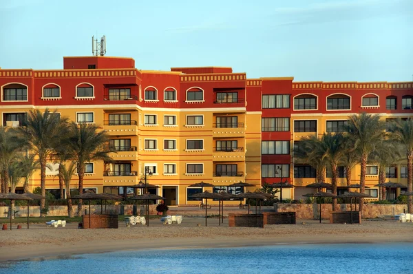 Plage de sable avec palmiers et grandes maisons de vacances au coucher du soleil — Photo