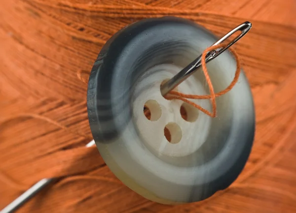 Botão com uma agulha em carretel de fio — Fotografia de Stock