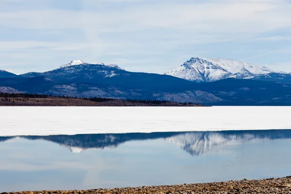Snötäckta berg speglas på sjön laberge, yukon, Kanada — Stockfoto