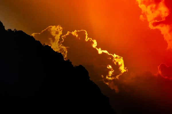 Solen går ner bakom berget siluett — Stockfoto