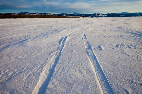 Rüzgârla oluşan kar yığını ve lastik izleri — Stok fotoğraf