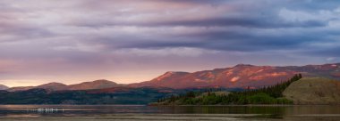 Distant Yukon mountains glowing in sunset light clipart