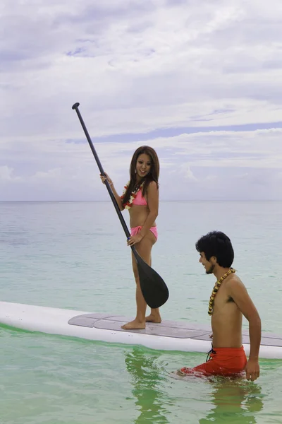 Beachboy uczy młodą kobietę do paddleboard — Zdjęcie stockowe