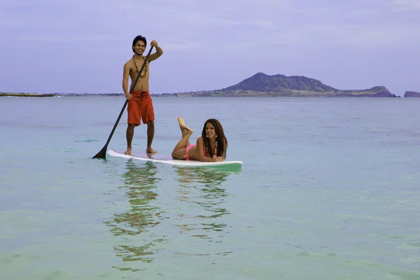 Beachboy con chica en bikini sobre tabla de paddle —  Fotos de Stock