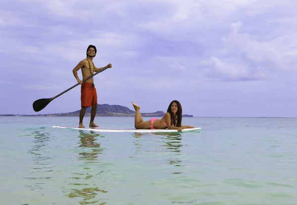 Beachboy mit Mädchen im Bikini auf Paddelbrett — Stockfoto